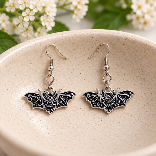 Black fanged bat earrings in a speckled ceramic bowl