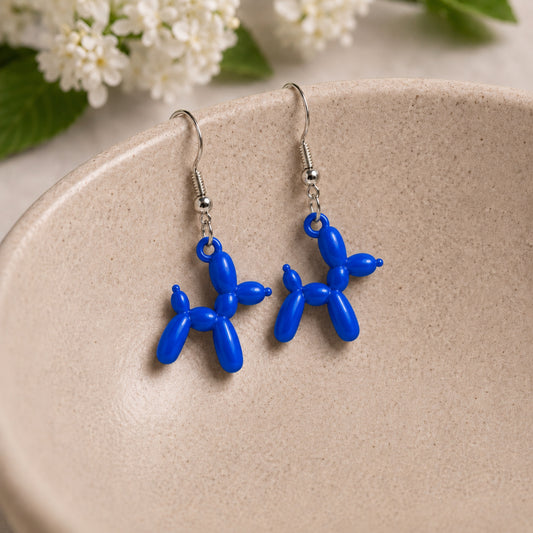 Blue Balloon Dog Earrings hanging from a ceramic bowl