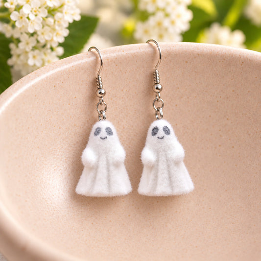 Cheeky Ghost Earrings hanging from a pale pink speckled ceramic bowl