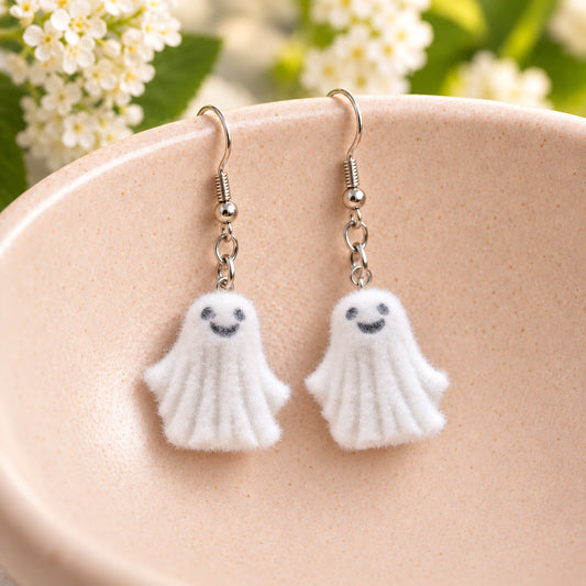 Dancing Ghost Earrings hanging from the rim of a pale pink speckled ceramic bowl