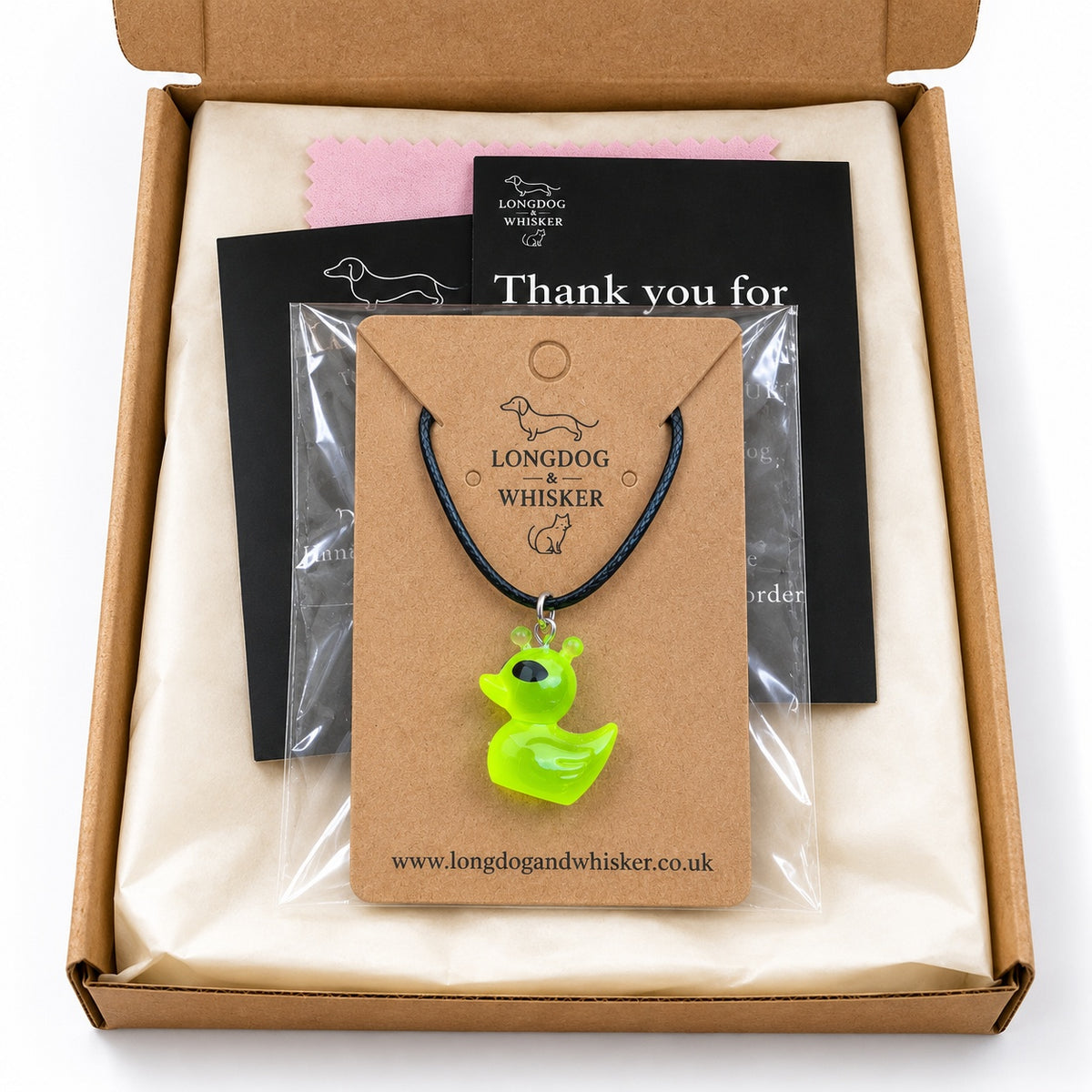 Green alien duck black cord necklace presented on its card in gift-ready packaging