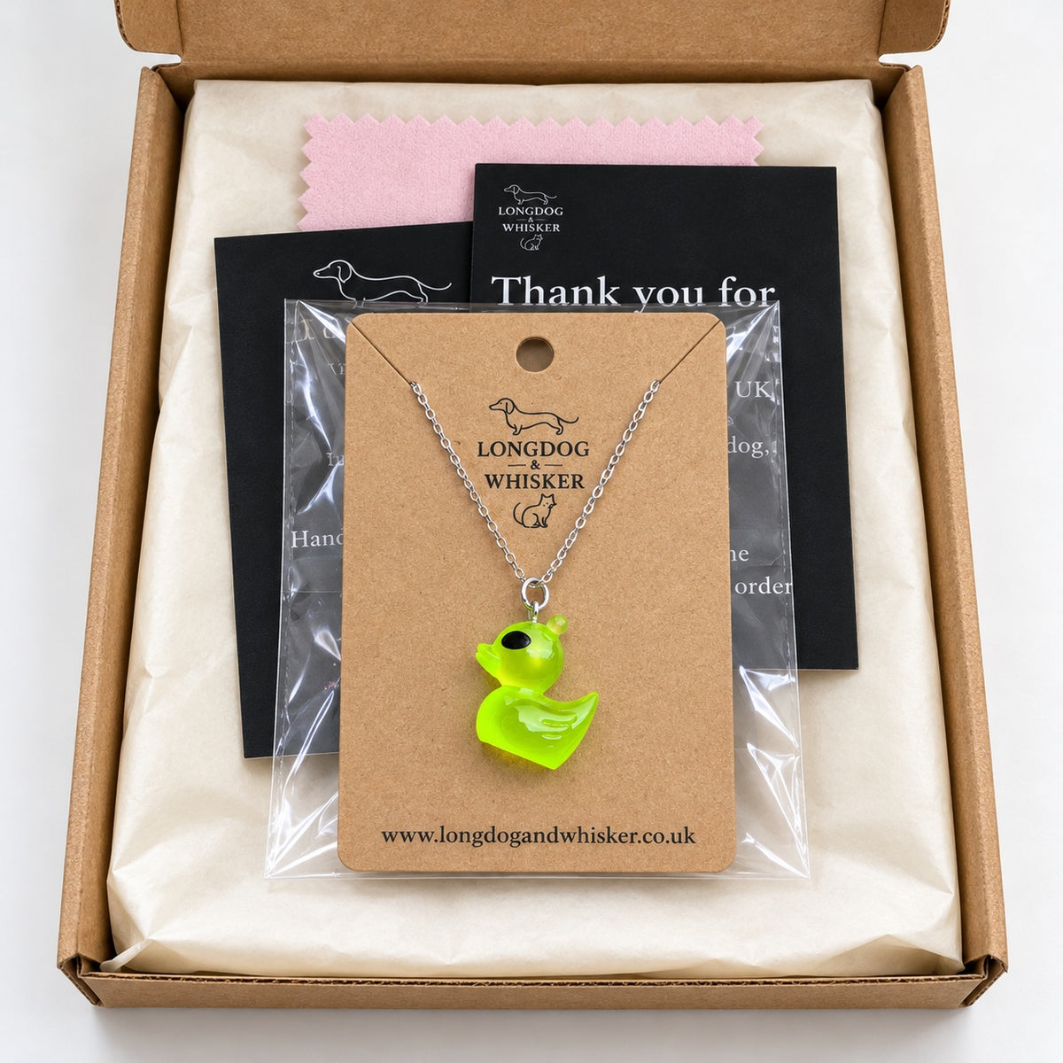 Green alien duck necklace on its product card in gift-ready packaging
