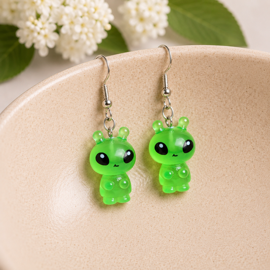 Little Green Alien Earrings hanging over a ceramic bowl