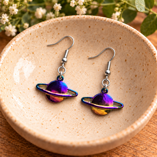 Iridescent Saturn planet earrings displayed in a speckled ceramic bowl