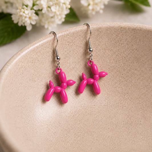 Pink Balloon Dog Earrings hanging from a ceramic bowl