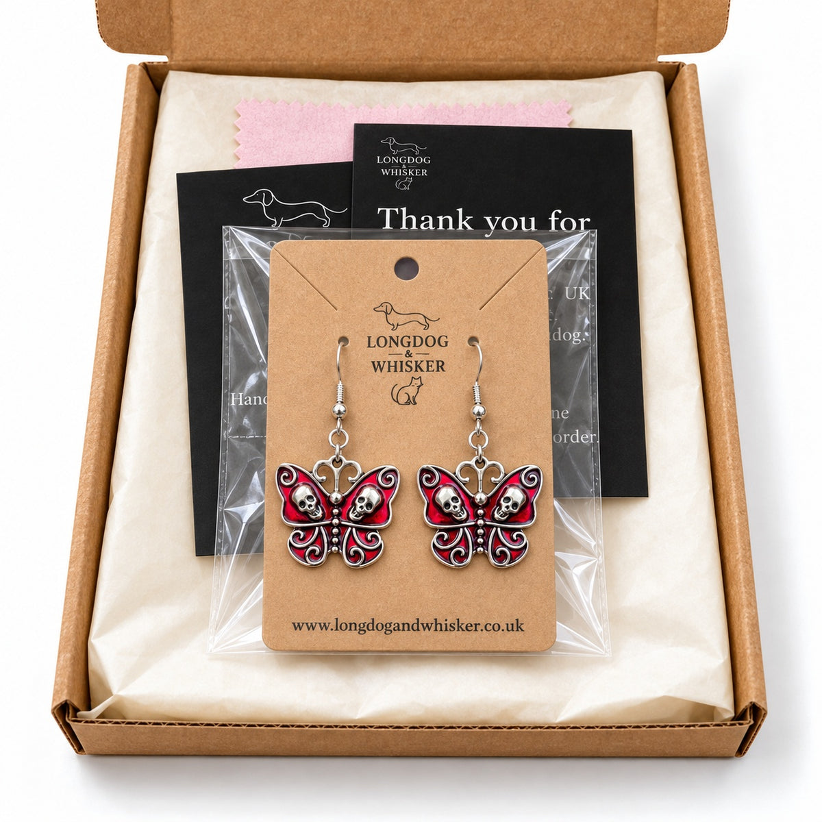 Red skull butterfly earrings on their kraft card in Longdog & Whisker gift packaging