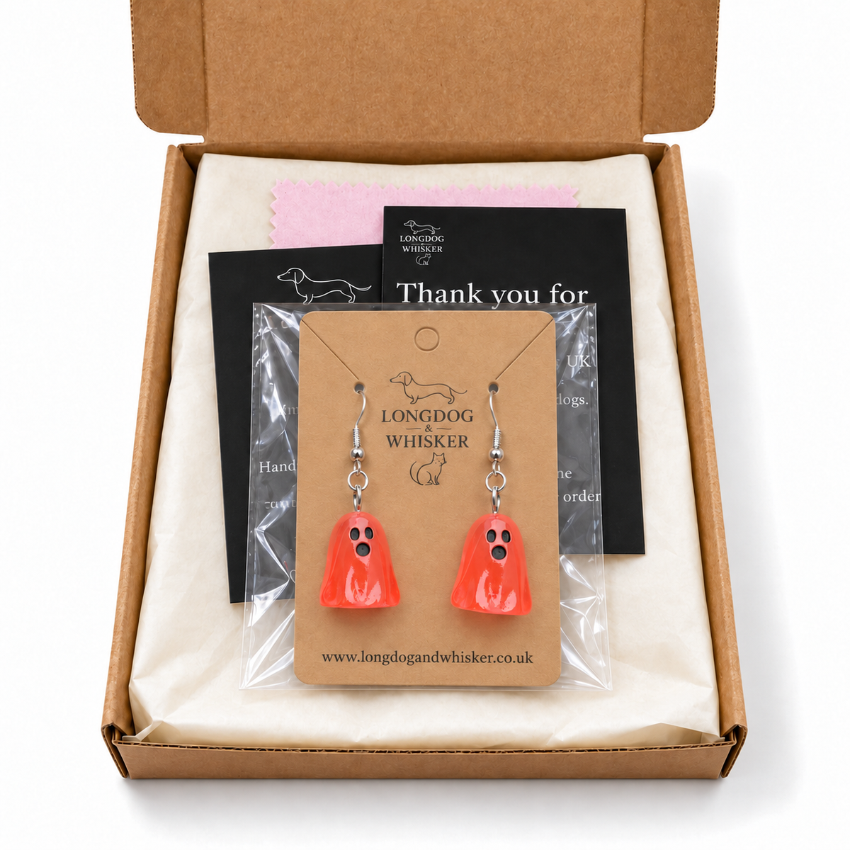 Translucent pale red ghost earrings on their display card in a kraft postal box