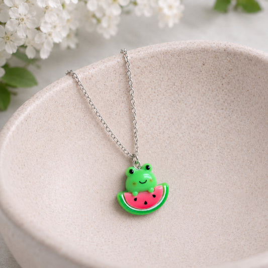 Watermelon Frog Necklace hanging over a ceramic bowl