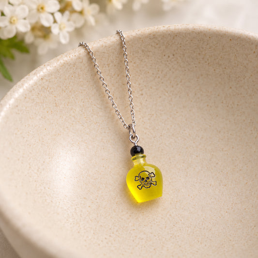 Yellow poison bottle necklace resting in a speckled ceramic bowl.