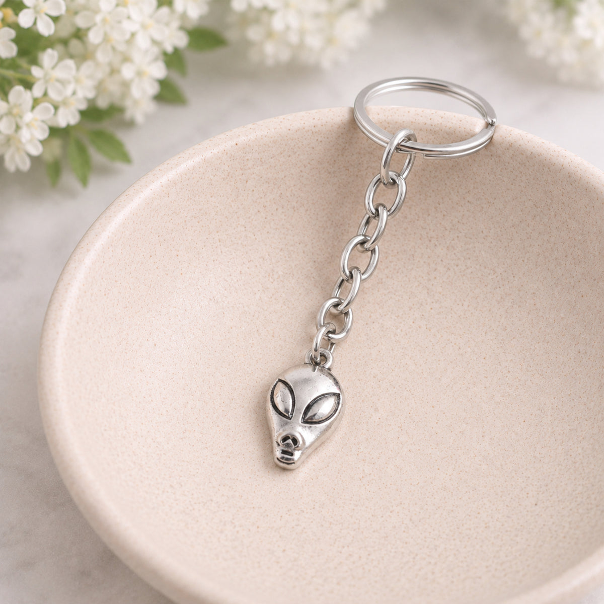 Alien head key chain bag charm styled in a ceramic bowl