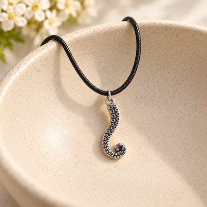 Antique silver tentacle necklace with black braided cord in a ceramic bowl