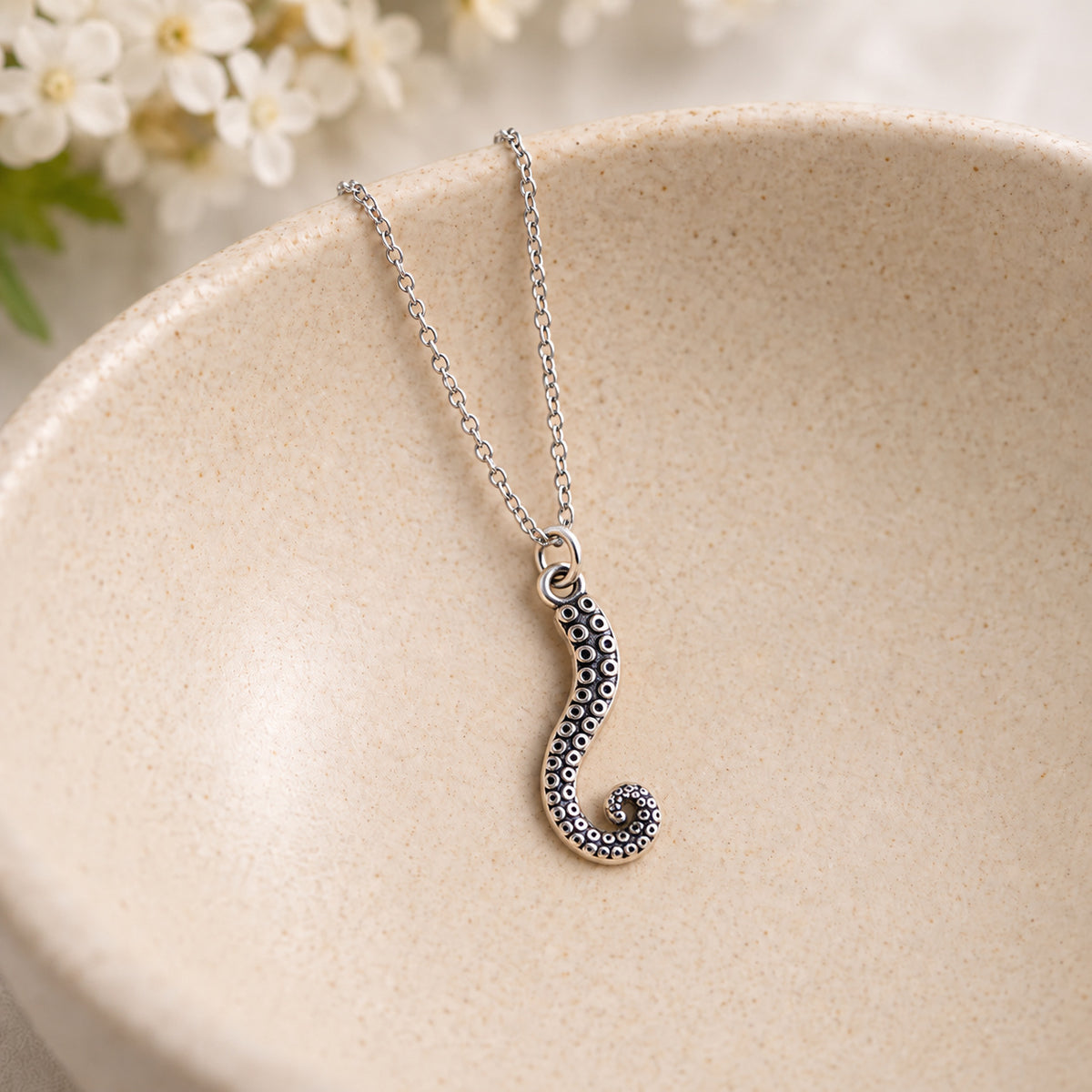 Antique silver tentacle necklace with silver chain in a ceramic bowl