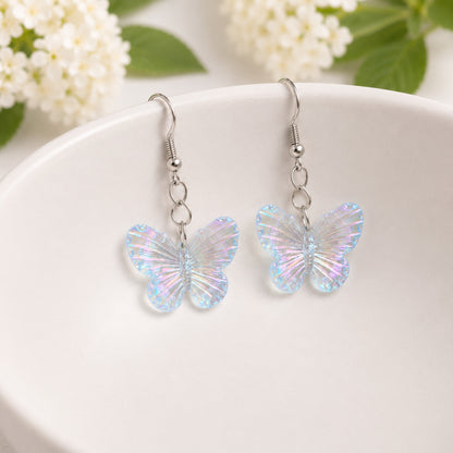 Aurora Butterfly Earrings in blue hanging from a white bowl