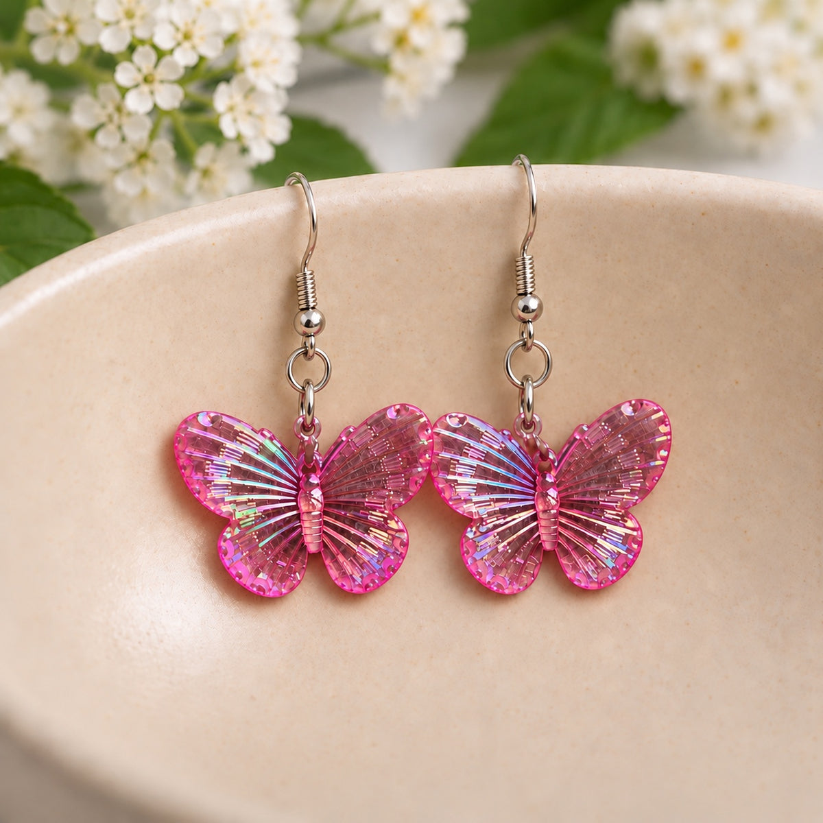 Hot Pink Aurora Butterfly Earrings resting in a speckled ceramic bowl