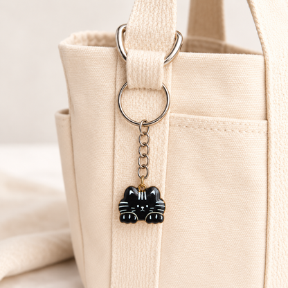 Black cat keyring attached to a cream canvas bag