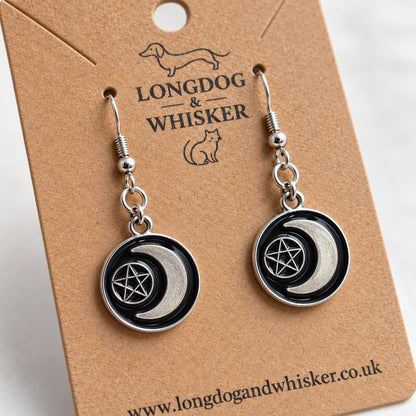 Close-up of glossy black crescent moon and pentagram charms with silver-tone fittings