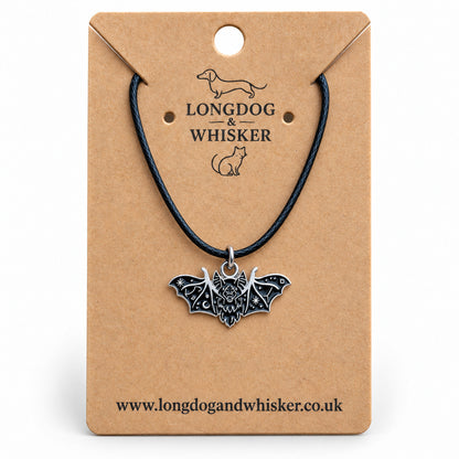 Black fanged bat necklace on a black cord, displayed on a Longdog & Whisker kraft card