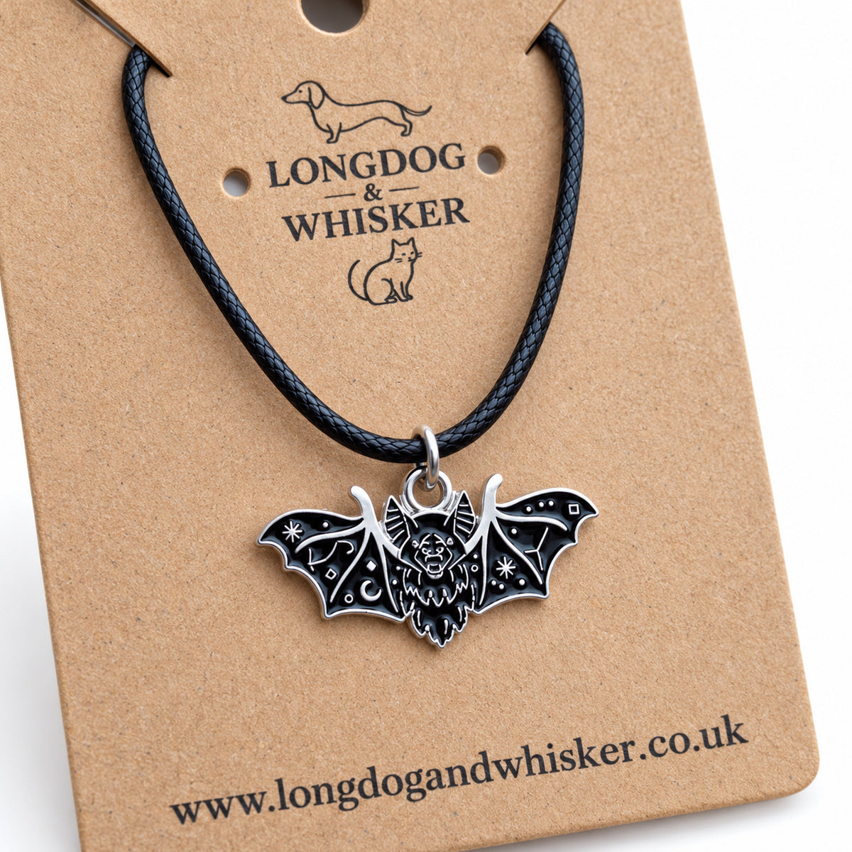 Close-up of the black fanged bat necklace on black cord showing its face and silver-tone wing patterns