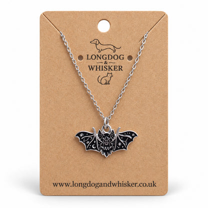 Black fanged bat necklace on a silver chain, displayed on a Longdog & Whisker kraft card