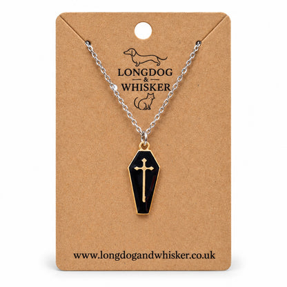 Black coffin necklace with a gold-tone cross on a silver-tone chain, displayed on a Longdog & Whisker kraft card