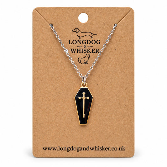 Black coffin necklace with a gold-tone cross on a silver-tone chain, displayed on a Longdog & Whisker kraft card