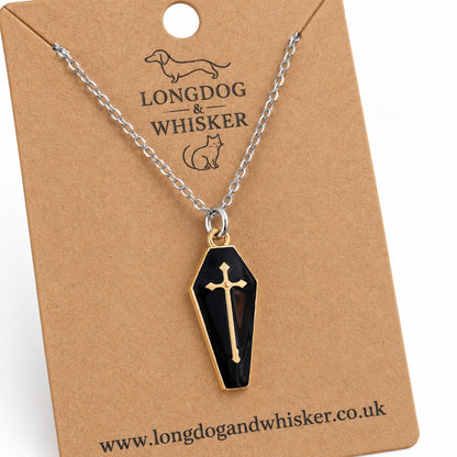 Close-up of the black coffin pendant, gold-tone cross and border, and fine silver-tone chain