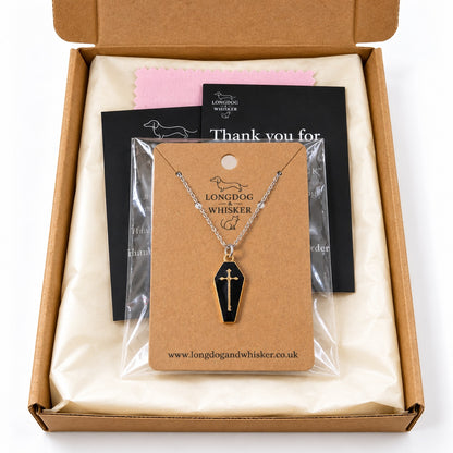 Black and gold-tone coffin cross necklace on a silver-tone chain in Longdog & Whisker postal packaging