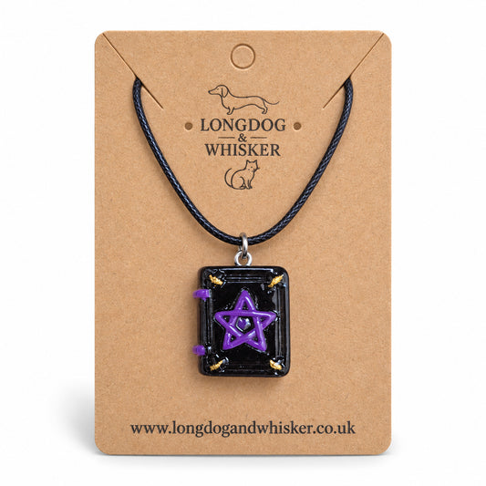Black and purple spellbook necklace on black cord on a Longdog & Whisker kraft card against white