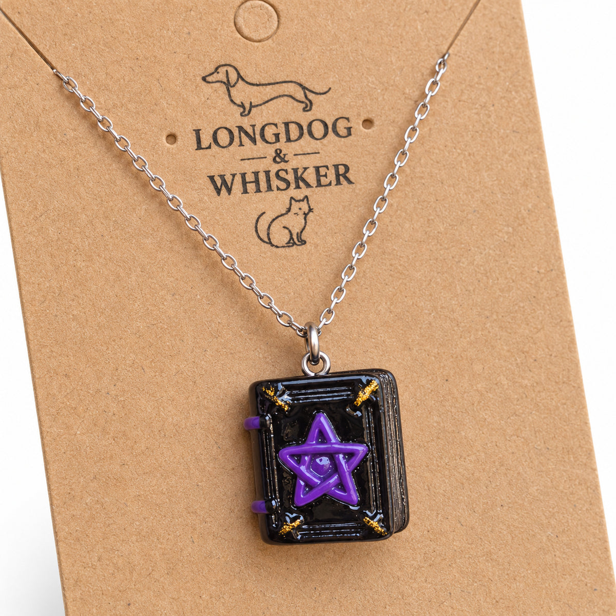 Close-up of the spellbook necklace showing the purple pentagram, gold-coloured corners and book page detail