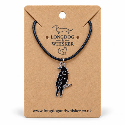 Black raven crescent moon necklace on black cord, displayed on a Longdog & Whisker kraft card