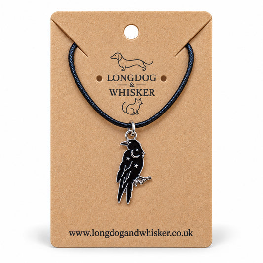 Black raven crescent moon necklace on black cord, displayed on a Longdog & Whisker kraft card