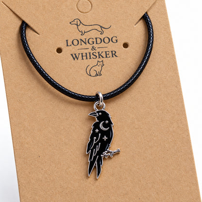 Close-up of the black raven pendant with silver-tone moon and star details on black cord