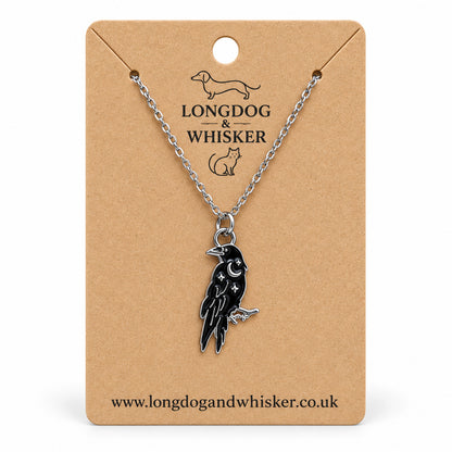 Black raven crescent moon necklace on a silver chain, displayed on a Longdog & Whisker kraft card