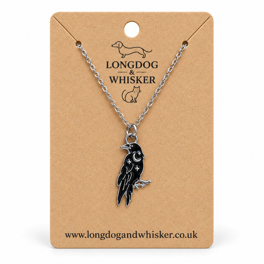 Black raven crescent moon necklace on a silver chain, displayed on a Longdog & Whisker kraft card