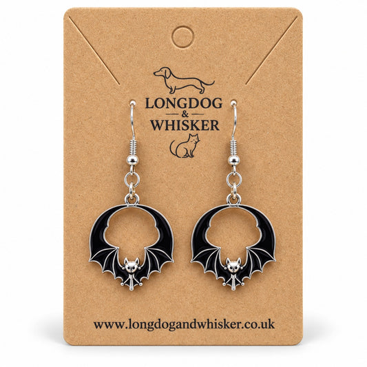 Black round wing bat drop earrings with silver-tone details on a Longdog & Whisker kraft card