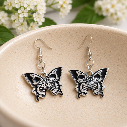 Double skull butterfly earrings in a speckled ceramic bowl