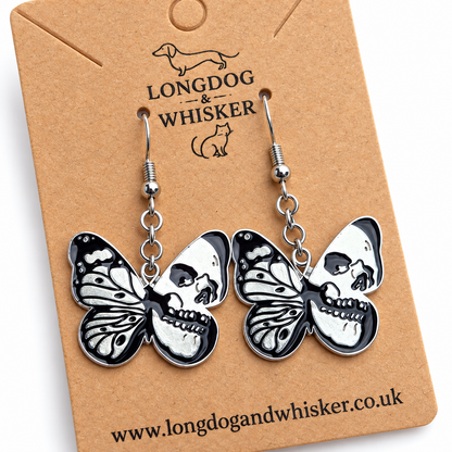 Close detail of black and silver skull butterfly drop earrings on a Longdog & Whisker card