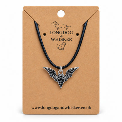 Black skeletal bat necklace on a black cord, displayed on a Longdog & Whisker kraft card