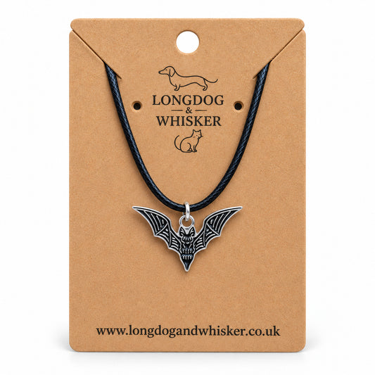 Black skeletal bat necklace on a black cord, displayed on a Longdog & Whisker kraft card