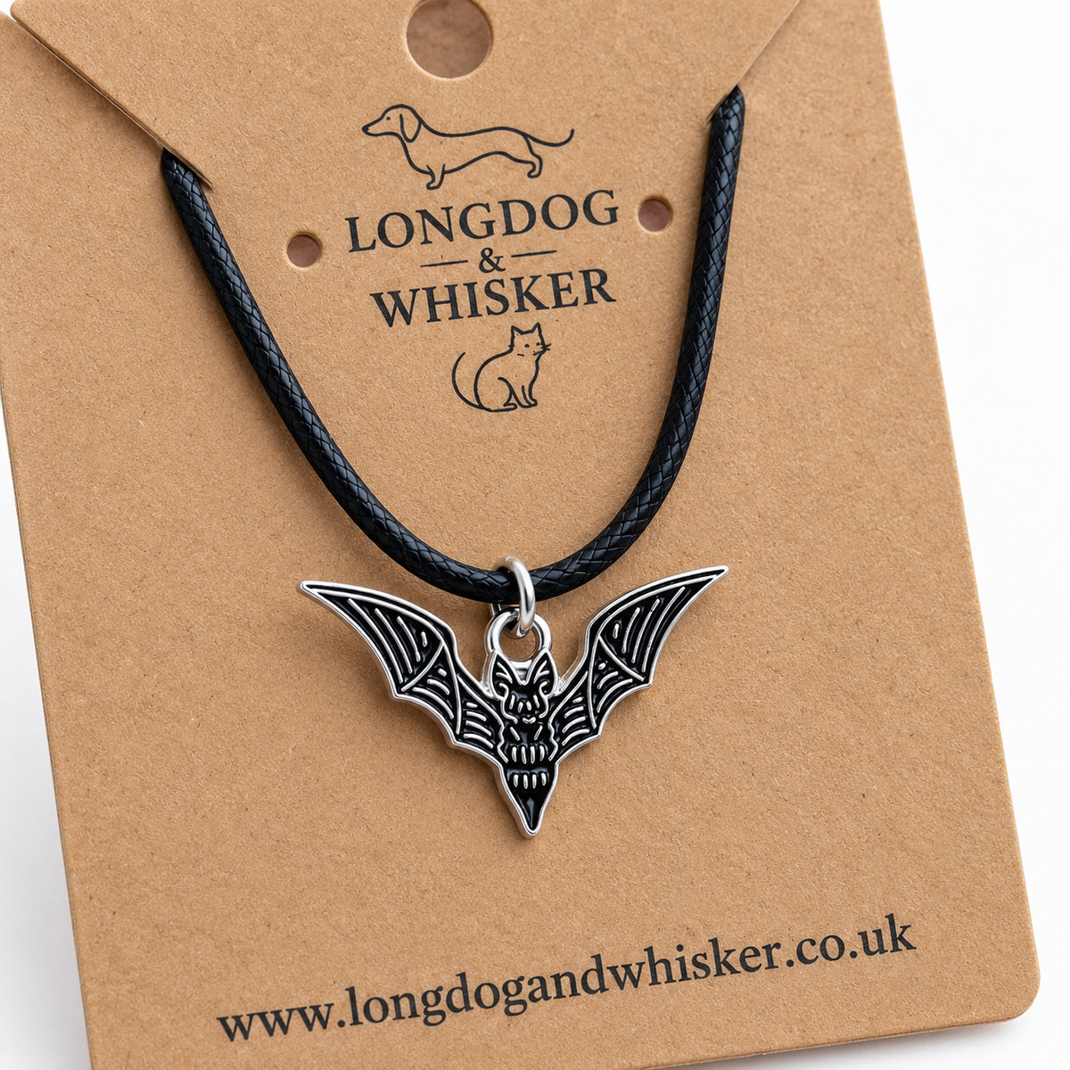 Close-up of the black skeletal bat necklace on black cord, showing its silver-tone bone detailing