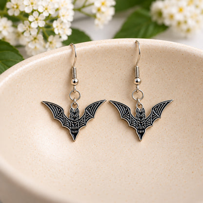 Black skeletal bat earrings displayed in a speckled ceramic bowl