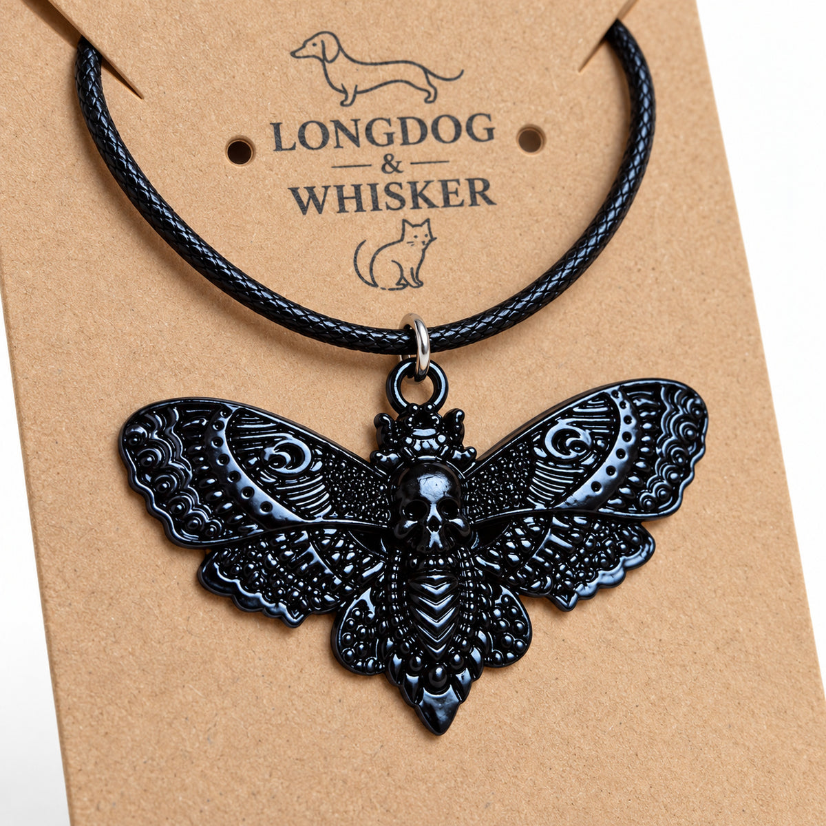 Close-up of the raised skull and ornate wing patterns on the black moth pendant and black cord