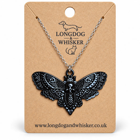 Black skull moth necklace on a silver chain, displayed on a Longdog & Whisker kraft card
