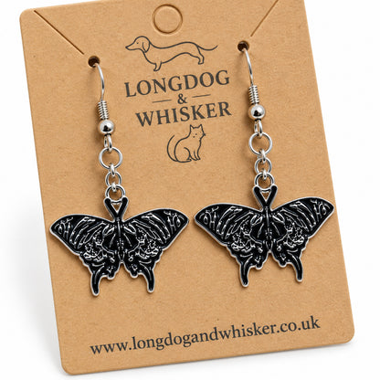 Close-up of black moth earrings with silver skull-like wing details