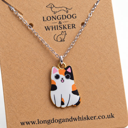 Close-up of the Calico Chonky Cat Necklace showing its patchwork markings and gold-tone edging