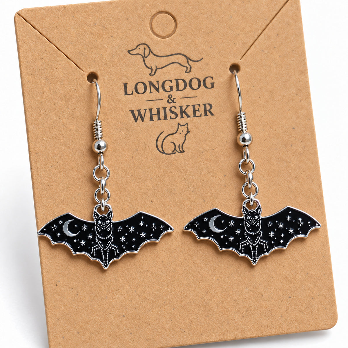 Close-up of glossy black bat earrings with silver moon and star details