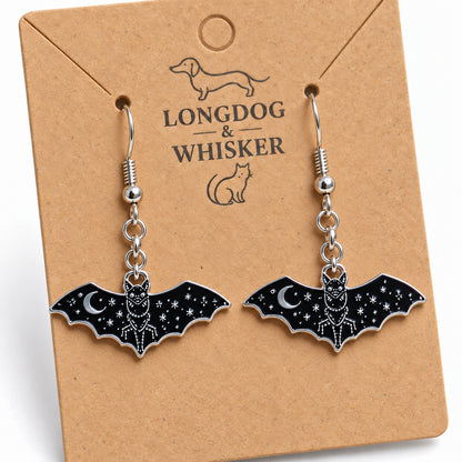 Close-up of glossy black bat earrings with silver moon and star details