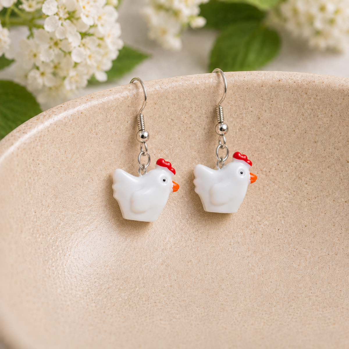 Chicken Earrings hanging over a ceramic bowl