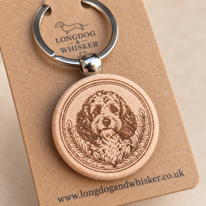 Close-up of Cockapoo portrait and leafy border on the wooden keyring, with silver connector