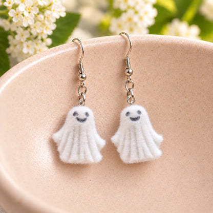 Dancing Ghost Earrings hanging from the rim of a pale pink speckled ceramic bowl
